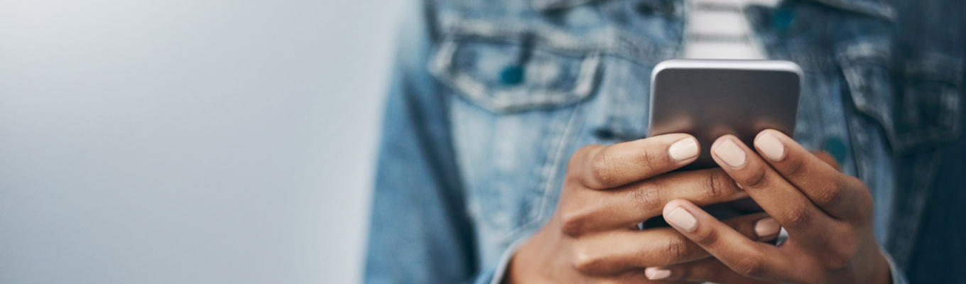 Person in jean jacket holding phone -- About Us